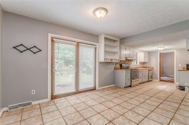 227 Margo Trl, Rome, GA 30161 - kitchen with stainless steel range with electric cooktop, open shelves, baseboards, light tile patterned floors, and white cabinetry