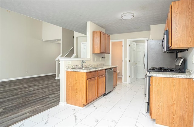 kitchen featuring a textured ceiling, sink, kitchen peninsula, and stainless steel appliances