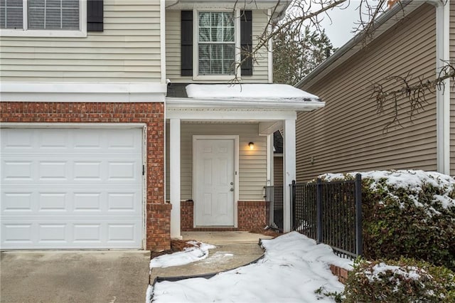 snow covered property entrance with a garage