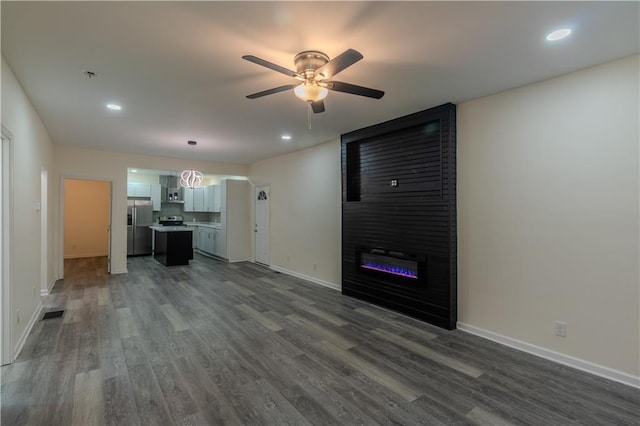 unfurnished living room featuring dark hardwood / wood-style floors, ceiling fan, and a fireplace