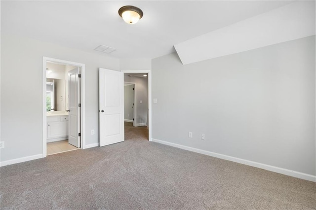 unfurnished bedroom with ensuite bathroom and light colored carpet