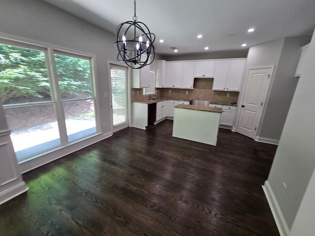 kitchen featuring plenty of natural light, dark hardwood / wood-style flooring, a kitchen island, decorative backsplash, and white cabinets