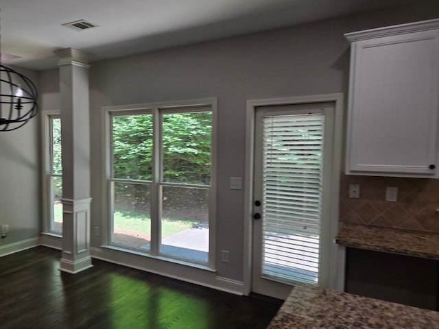 entryway featuring decorative columns, dark wood-type flooring, and a notable chandelier