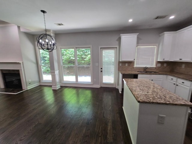 kitchen featuring white cabinetry, a center island, sink, and backsplash