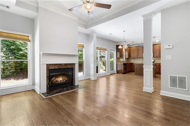 unfurnished living room with a premium fireplace, a wealth of natural light, decorative columns, and dark hardwood / wood-style floors