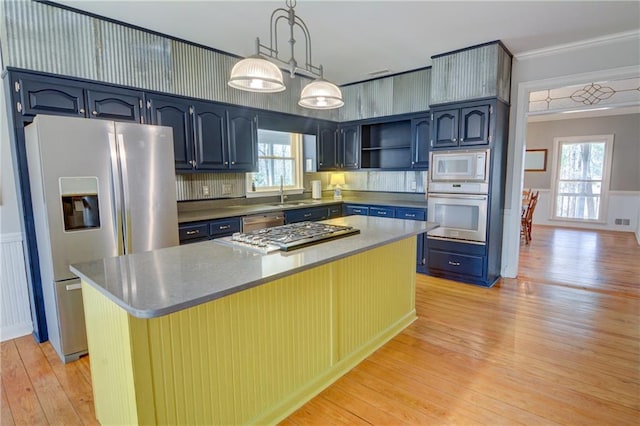 kitchen with hanging light fixtures, a center island, stainless steel appliances, blue cabinetry, and light hardwood / wood-style flooring