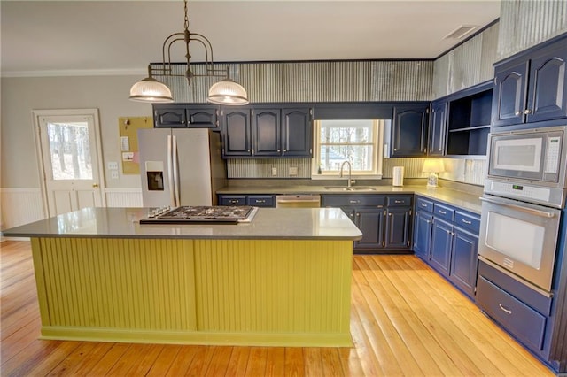 kitchen with appliances with stainless steel finishes, decorative light fixtures, sink, and a kitchen island