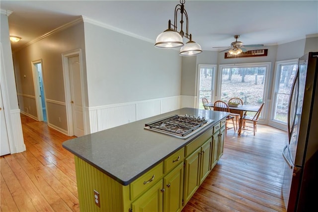 kitchen featuring a kitchen island, appliances with stainless steel finishes, green cabinets, light hardwood / wood-style floors, and crown molding