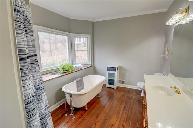 bathroom featuring hardwood / wood-style floors, ornamental molding, vanity, toilet, and a bath