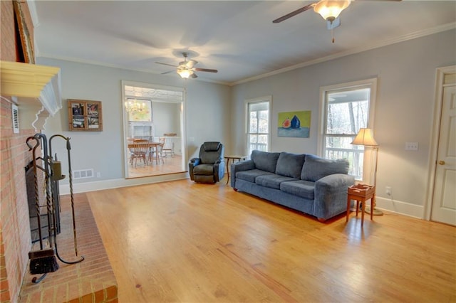 living room featuring crown molding, hardwood / wood-style flooring, a fireplace, and ceiling fan