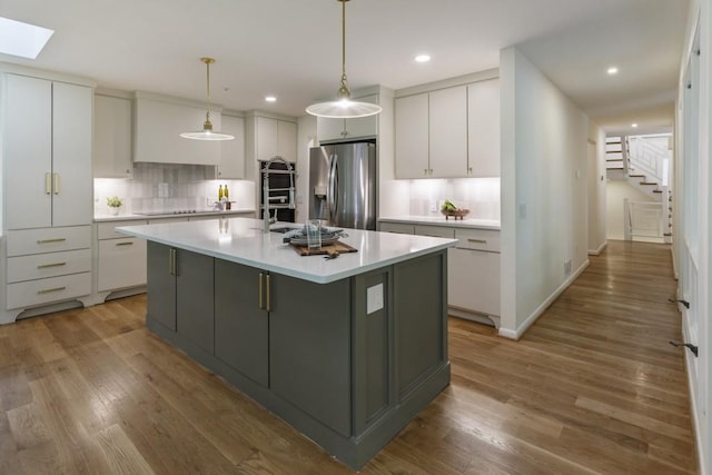 kitchen with backsplash, stainless steel refrigerator with ice dispenser, light wood-style flooring, and light countertops