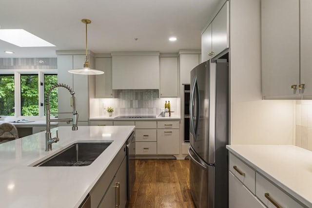 kitchen with a sink, light countertops, a skylight, and stainless steel appliances