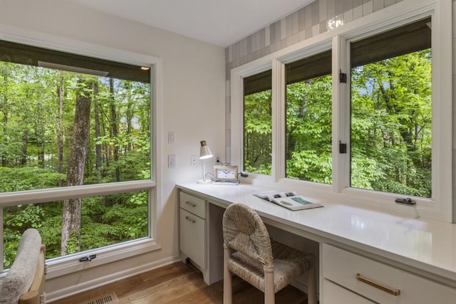 office space with baseboards, light wood finished floors, and built in desk