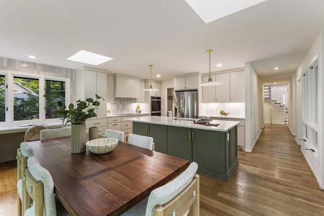 dining area featuring a skylight, stairway, recessed lighting, and wood finished floors