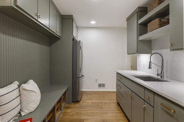 interior space with a sink, freestanding refrigerator, gray cabinetry, and light wood-type flooring
