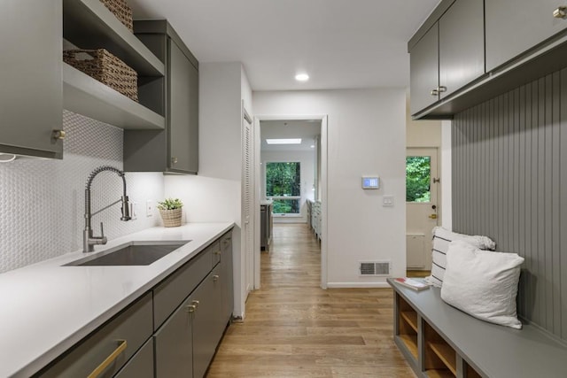 kitchen with open shelves, a sink, light wood-style floors, light countertops, and visible vents