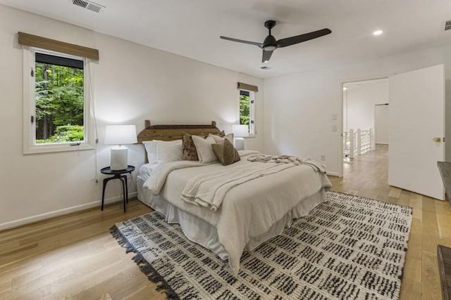 bedroom featuring baseboards, multiple windows, wood finished floors, and visible vents
