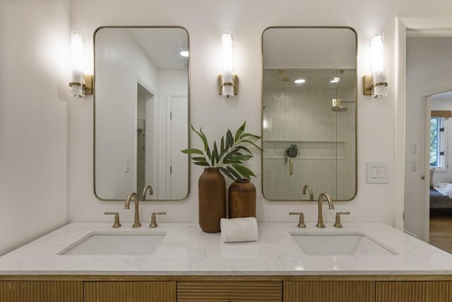 ensuite bathroom with double vanity, a sink, and a stall shower