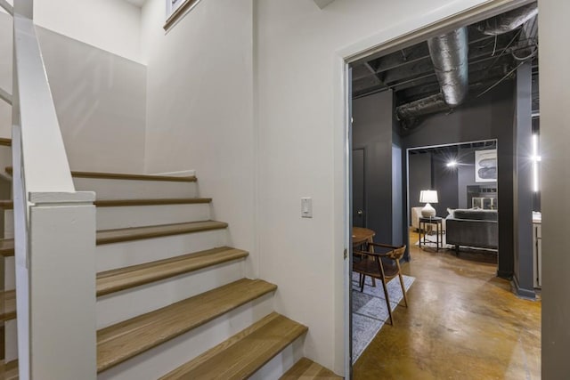staircase with concrete floors and a high ceiling
