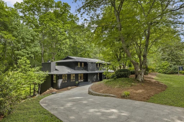 view of front facade with roof with shingles, a porch, and driveway