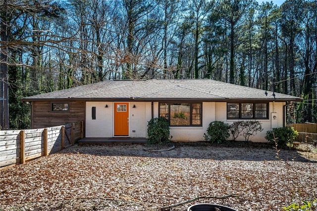 ranch-style house featuring fence, brick siding, and roof with shingles