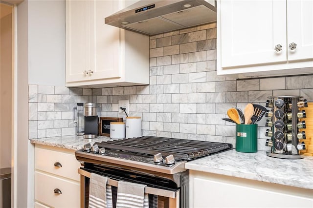 kitchen featuring under cabinet range hood, backsplash, white cabinets, and stainless steel gas stove