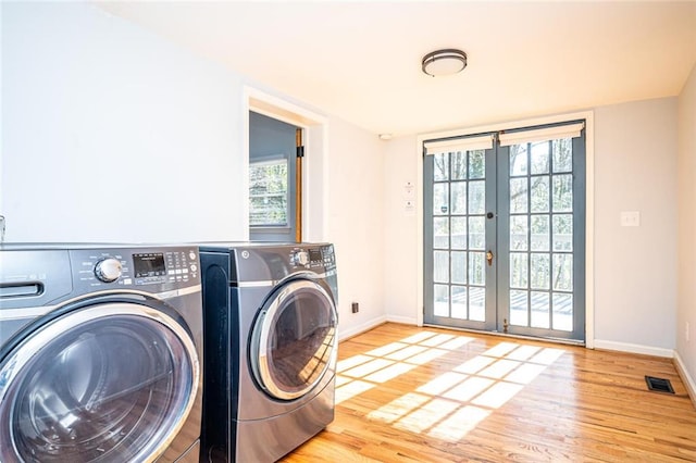 laundry room with laundry area, wood finished floors, french doors, and washing machine and clothes dryer