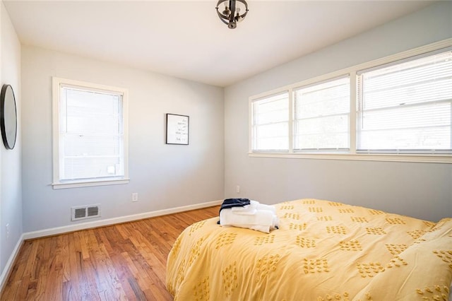 bedroom with wood finished floors, visible vents, and baseboards