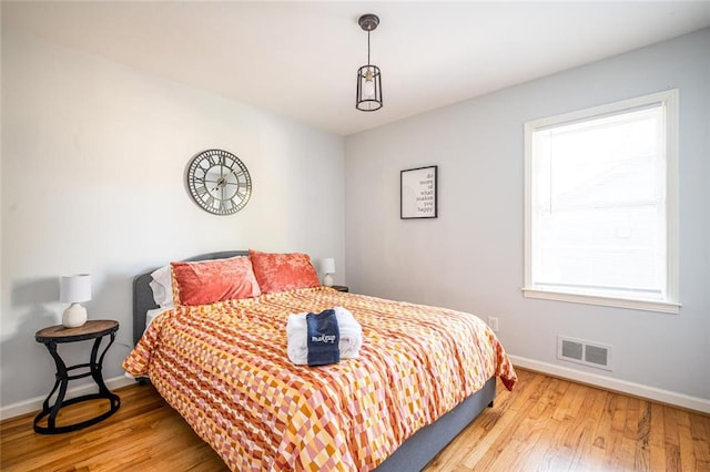 bedroom with wood finished floors, visible vents, and baseboards