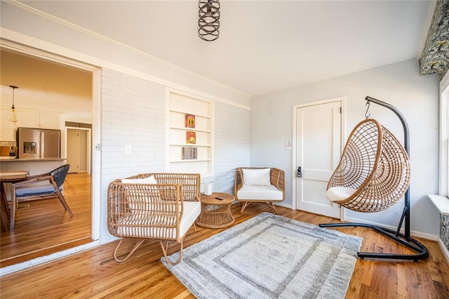 sitting room featuring built in features, light wood-style floors, and baseboards