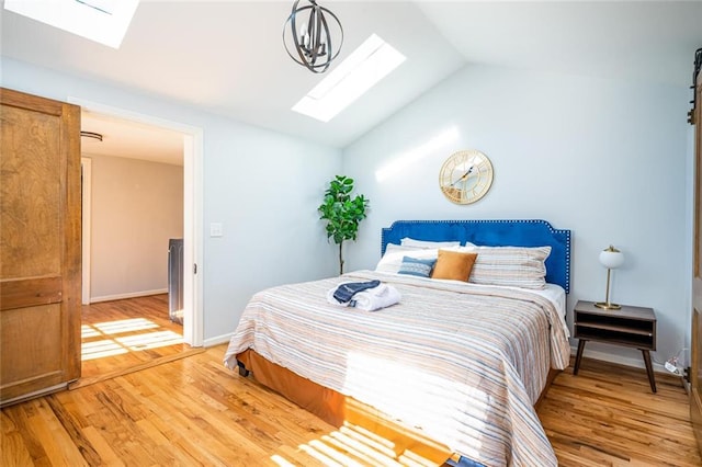 bedroom featuring baseboards, lofted ceiling with skylight, and light wood finished floors