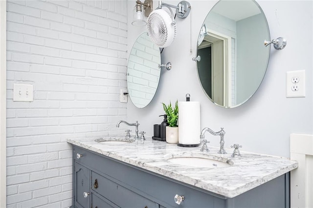 full bathroom with double vanity, brick wall, and a sink