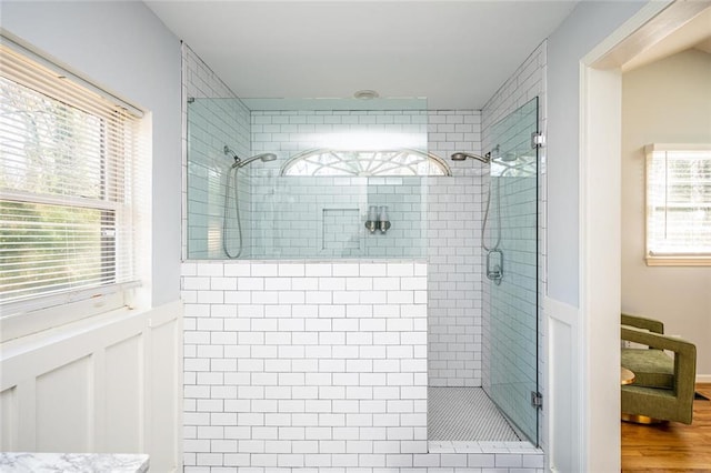 full bathroom featuring a wainscoted wall, wood finished floors, and a shower stall