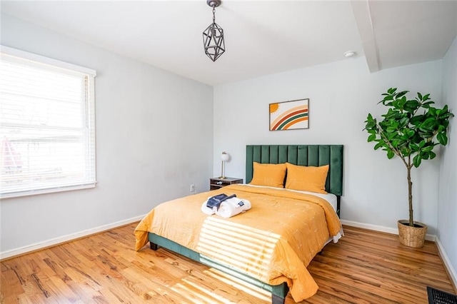 bedroom with visible vents, baseboards, and wood finished floors