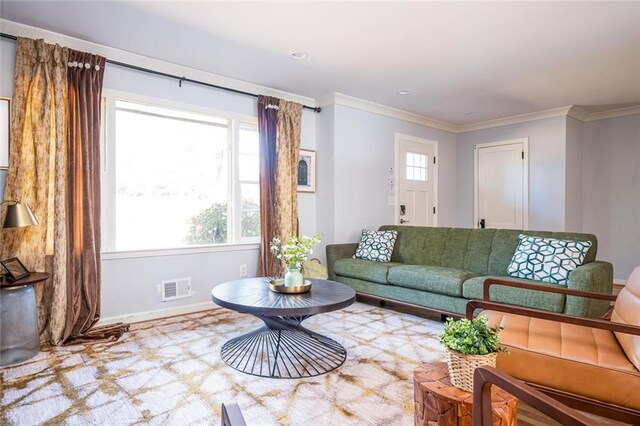 living room with visible vents, crown molding, and baseboards