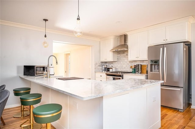 kitchen with wall chimney range hood, light wood-type flooring, decorative backsplash, stainless steel appliances, and white cabinetry