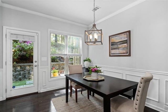 dining area with crown molding, a chandelier, dark wood-style floors, a decorative wall, and a wainscoted wall