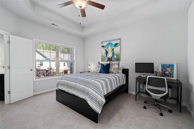 carpeted bedroom featuring baseboards, a tray ceiling, and a ceiling fan