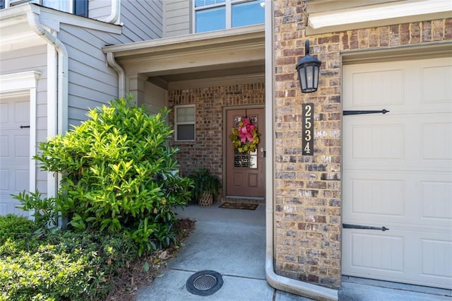 entrance to property with a garage and brick siding