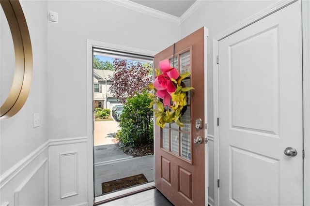 entrance foyer with crown molding, a wainscoted wall, and a decorative wall