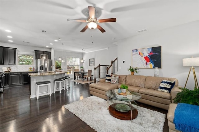 living room featuring a ceiling fan, dark wood-type flooring, recessed lighting, and stairs