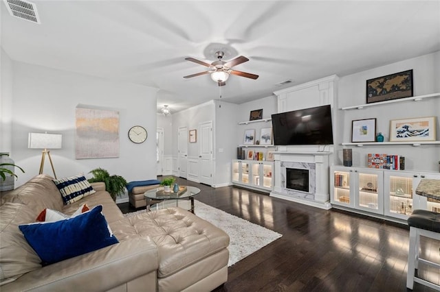 living area with a ceiling fan, dark wood finished floors, a premium fireplace, and baseboards