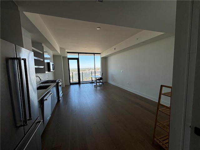 kitchen with dark wood-type flooring, appliances with stainless steel finishes, white cabinets, and expansive windows