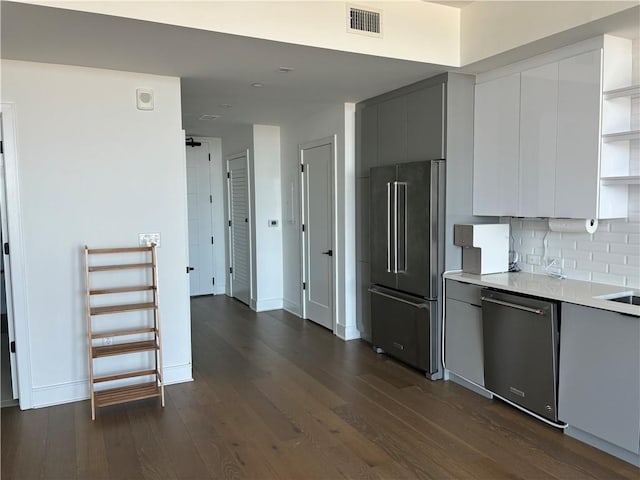 kitchen with dark wood-type flooring, stainless steel appliances, decorative backsplash, and white cabinetry