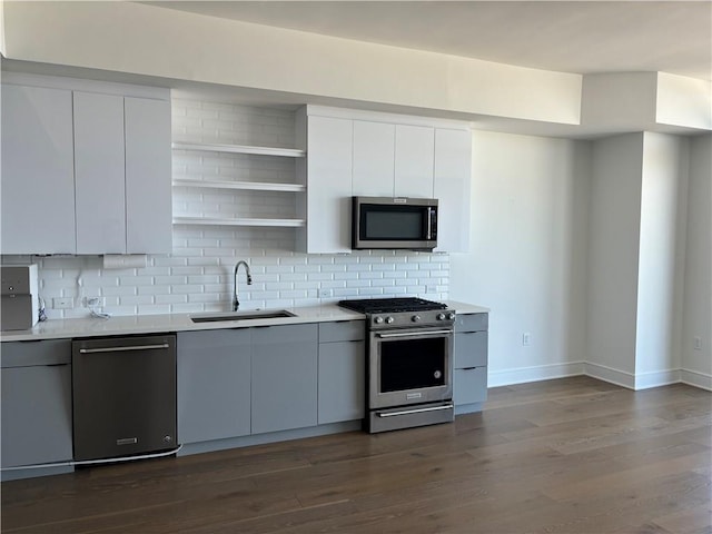 kitchen with dark hardwood / wood-style floors, stainless steel appliances, sink, white cabinetry, and tasteful backsplash