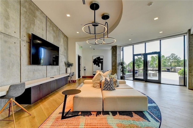 living room with a notable chandelier, light hardwood / wood-style flooring, and a wall of windows