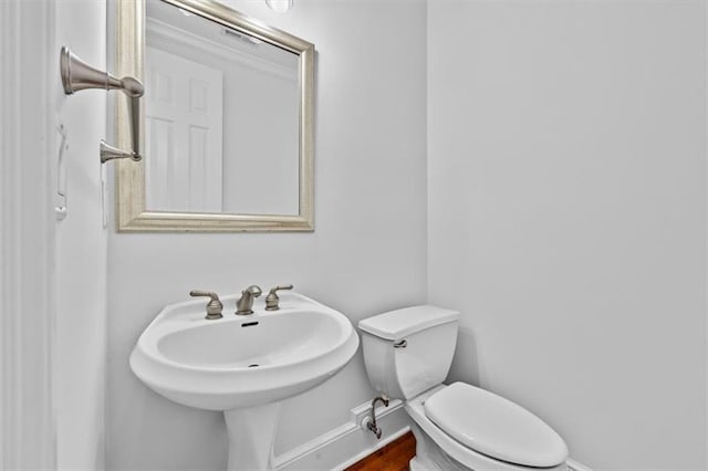 half bath featuring a sink, baseboards, and toilet