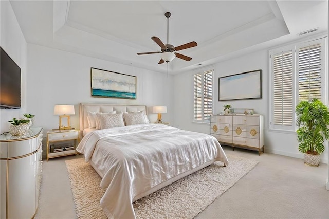 carpeted bedroom with a raised ceiling, baseboards, a ceiling fan, and visible vents