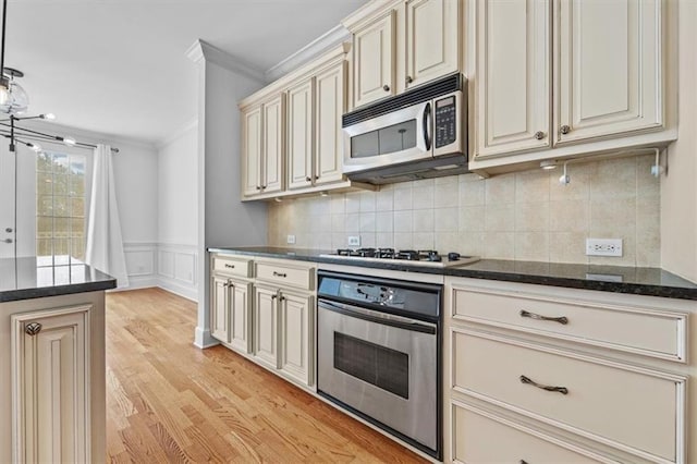 kitchen featuring cream cabinets, tasteful backsplash, light wood-type flooring, ornamental molding, and stainless steel appliances