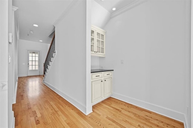 corridor featuring crown molding, light wood-style flooring, stairs, recessed lighting, and baseboards